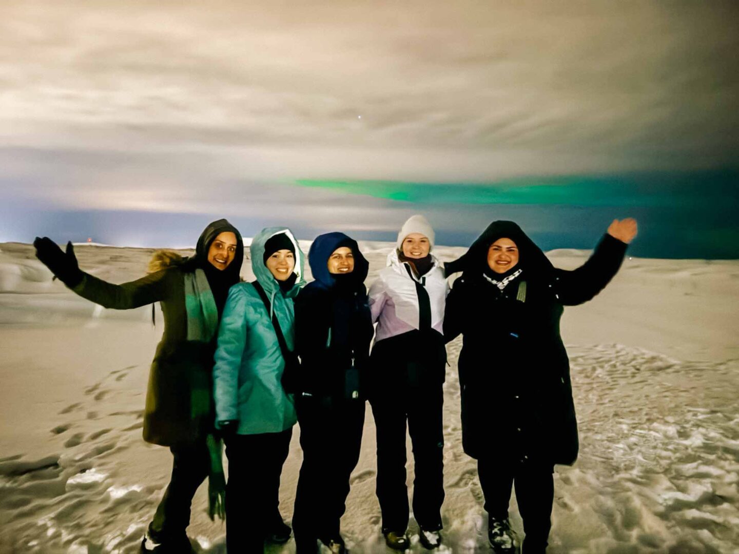 4 day iceland itinerary, group of 5 women with the Northern Lights behind them - 4 day iceland itinerary, group of 5 women with the Northern Lights behind them