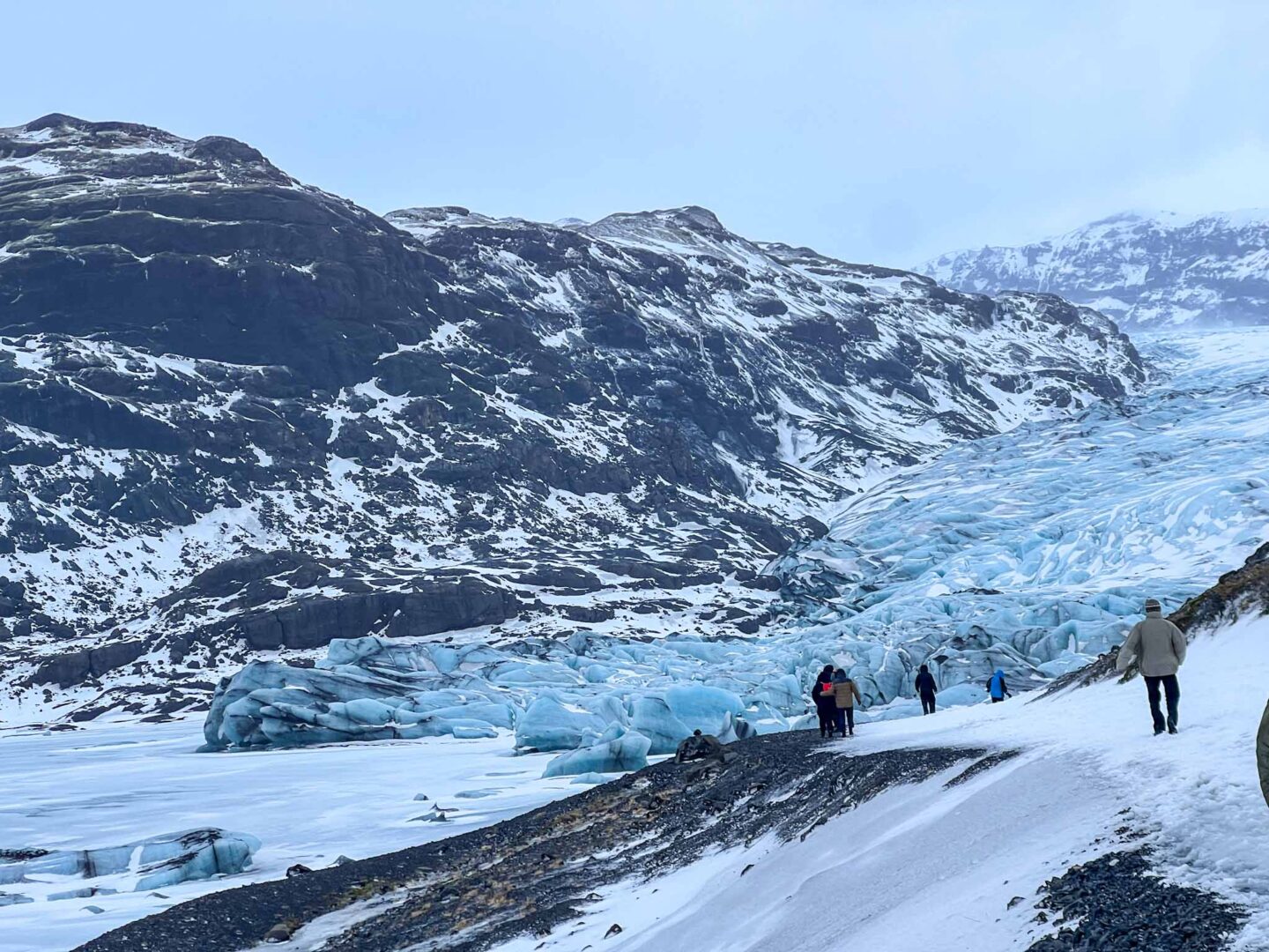 what to wear in Iceland in winter, tourists walking towards glacier in winter in iceland - what to wear in Iceland in winter, tourists walking towards glacier in winter in iceland