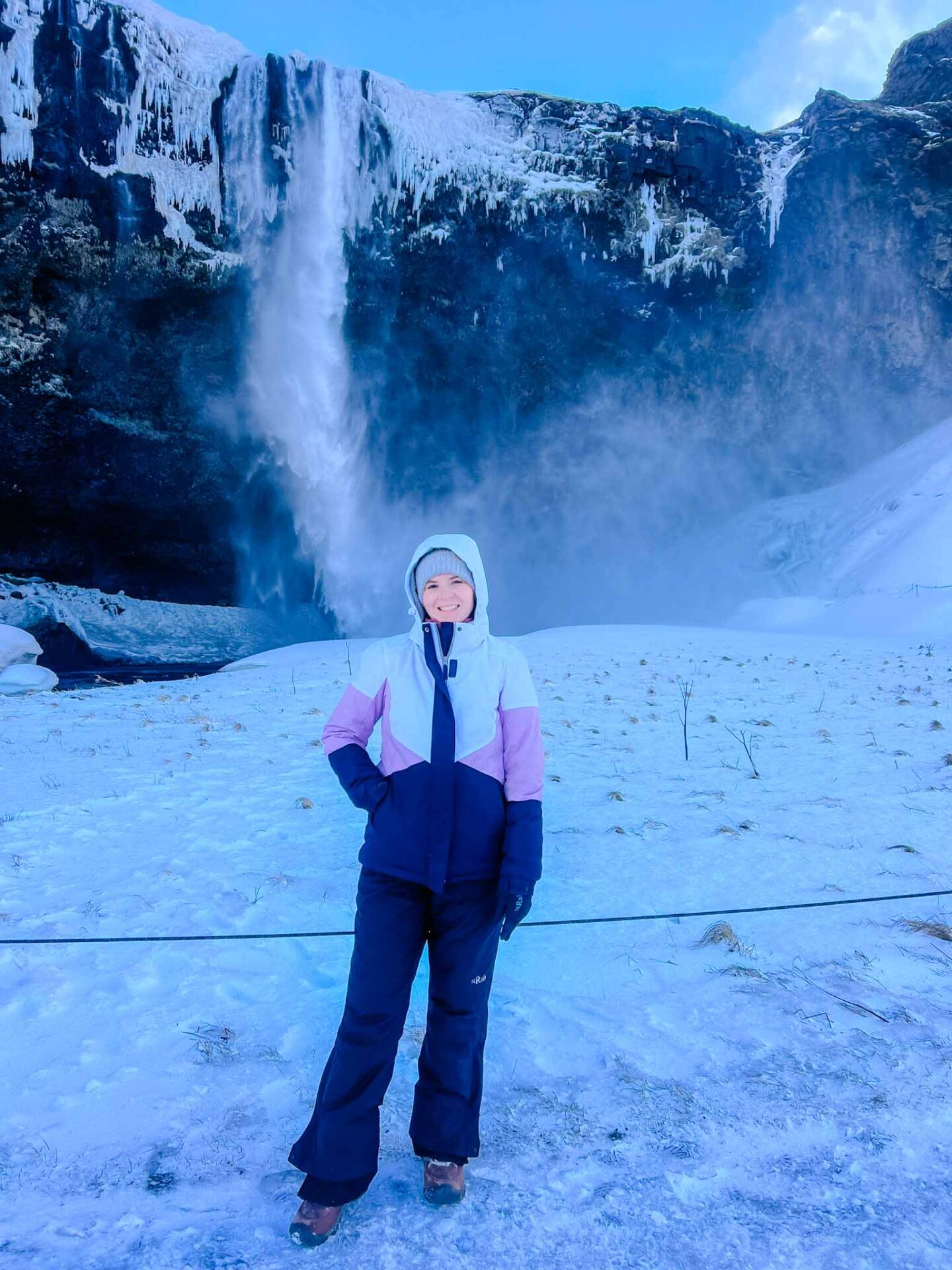 what to wear in Iceland in winter, Ellie wearing ski jacket at iceland waterfall - what to wear in Iceland in winter, Ellie wearing ski jacket at iceland waterfall